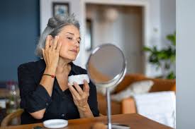 Femme devant son miroir qui de met une crème de beauté